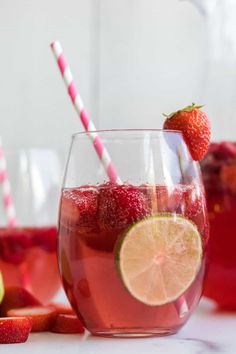 strawberry lemonade in a glass with strawberries and limes on the table next to it