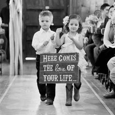 two children are walking down the aisle holding signs that read here comes the love of your life