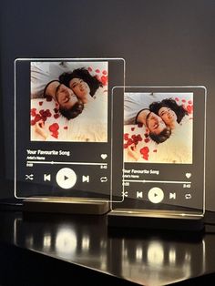 two glass photo frames sitting on top of a table next to each other with an mp3 player in front of them