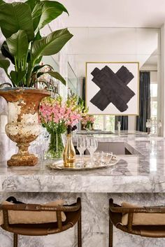 a marble dining room table with two vases and flowers on it, surrounded by chairs