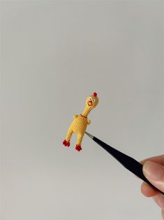 a hand holding a tiny yellow giraffe on top of a black marker with a red nose