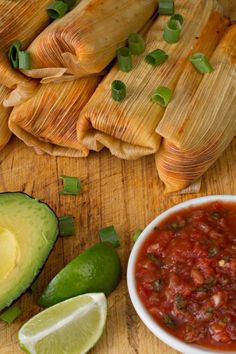 tamales with salsa and avocado on a cutting board