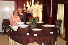 two women standing in front of a table with plates on it