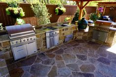 an outdoor kitchen with stone counter tops and grills