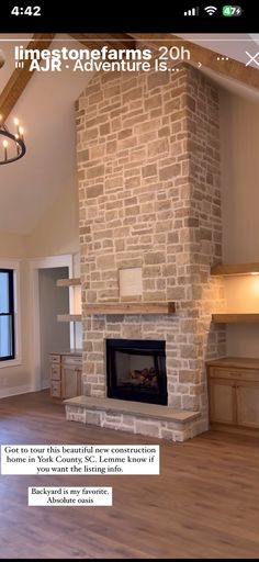 an image of a living room with wood flooring and stone fireplace in the center