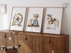 three framed pictures hang on a wooden cabinet