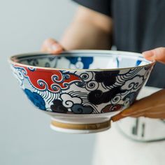 a person is holding a bowl with designs on it and their hands are in the bowl