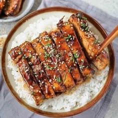 a plate with rice, meat and chopsticks on it