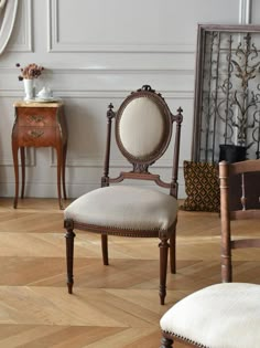 an antique chair and two side tables in a room with wood flooring, white walls and wooden parqueted floors