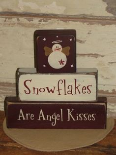 a wooden sign that says snowflakes are angel kisses on top of each other