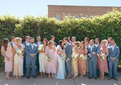 a group of people standing next to each other in front of some bushes and trees