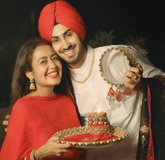 a man and woman pose for a photo while holding a plate with a cake on it