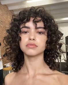 a woman with curly hair is posing for the camera