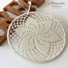 a white doily with wooden letters on the side next to it and another item in the background