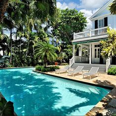 a house with a swimming pool in front of it and trees surrounding the pool area