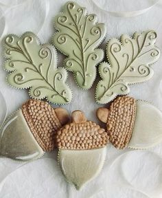 three cookies decorated with leaves and acorns on top of a white table cloth