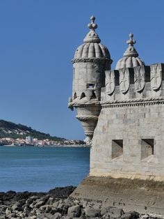 an old stone building sitting next to the ocean