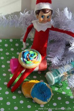 an elf is sitting on top of a christmas tree next to some cookies and candy