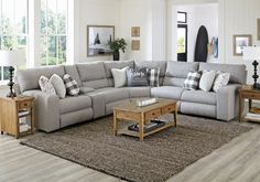 a living room with blue walls and gray furniture in the center, along with a large ottoman