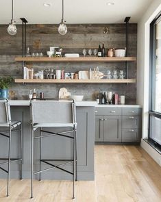 a kitchen with two bar stools in front of the sink and open shelving