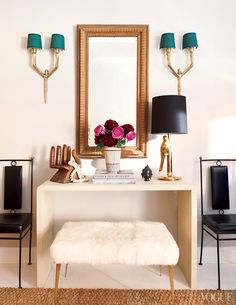 a room with two chairs, a table and a mirror on the wall above it