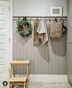 a wooden bench sitting next to a wall with two coats hanging on it's hooks