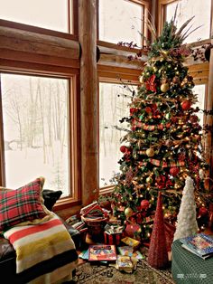 a decorated christmas tree sitting in the corner of a living room next to a window