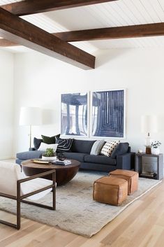 a living room with white walls and wooden beams on the ceiling is furnished with modern furniture