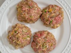 four hamburger patties on a white plate, ready to be eaten and put in the oven