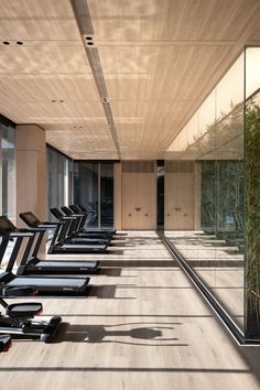 there are many treadmills lined up in the gym with mirrors on the wall