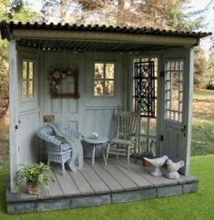 a small wooden shed with chairs on the porch