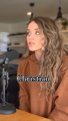 a woman sitting at a table in front of a microphone with the words christian on it