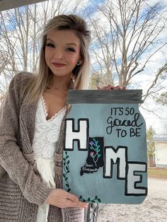 a woman holding up a sign that says it's so good to be home