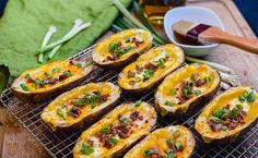 baked potatoes with bacon and green onions on a cooling rack next to a bowl of beer