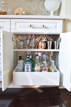 an open cabinet filled with bottles and glasses