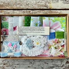 an open box filled with different types of buttons and lace on top of a wooden table