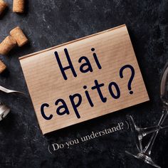 a piece of paper with the words hai capito? written on it next to wine glasses and corkscrews