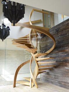 a wooden spiral staircase with chandelier hanging from it's sides in a room