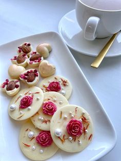 there are some cookies that have been decorated with pink roses and pearls on the plate