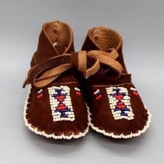 a pair of brown baby shoes with beading on them