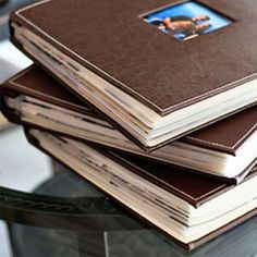 a stack of books sitting on top of a glass table next to a laptop computer