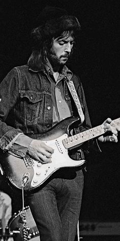 a black and white photo of a man playing an electric guitar