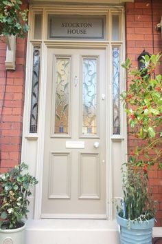 the front door to stockton house with potted plants on either side and glass paneled windows