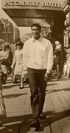 an old photo of a man walking down the street in front of piccadilly hotel