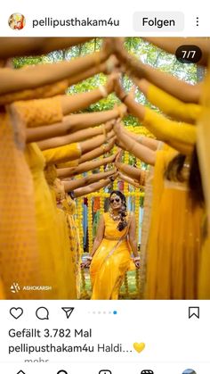 a woman in yellow dress standing between two rows of dresses with her hands on the hips