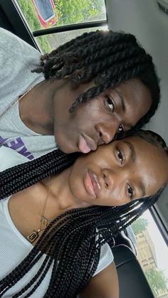 two people are posing for a photo in the back of a car, one is wearing braids and the other is looking at the camera