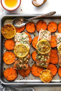 salmon and sweet potatoes on a baking sheet with lemons, garlic, and seasoning