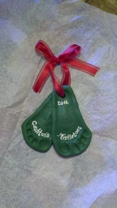 two green mittens with red ribbon tied around them on a white sheeted surface