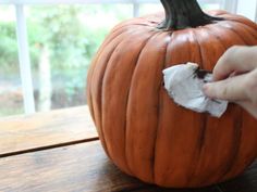 someone is peeling paper from a pumpkin on a wooden table in front of a window