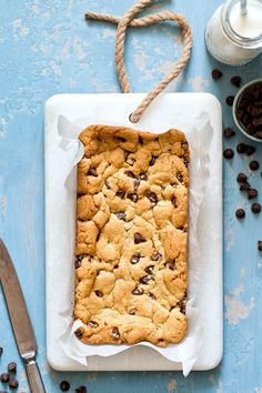 chocolate chip cookie bars on a plate next to coffee beans and a glass of milk